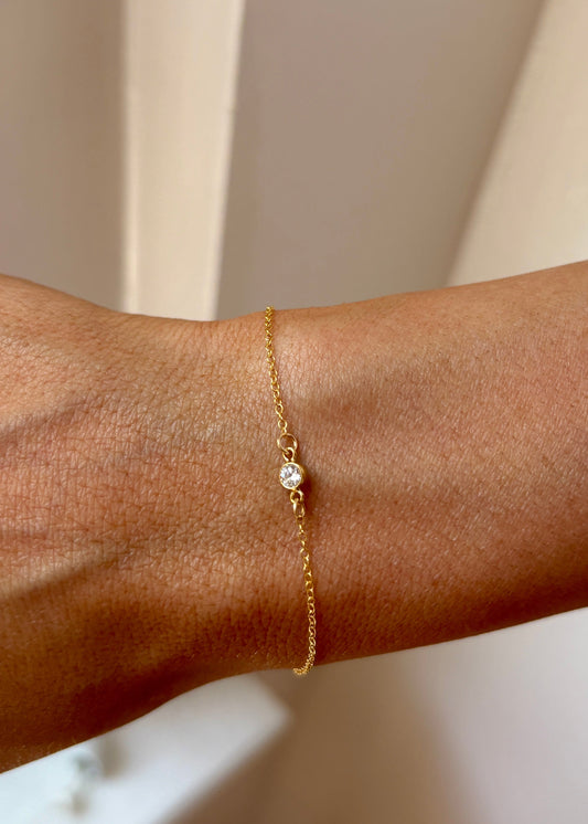 Gold bracelet on a wrist with a neutral background