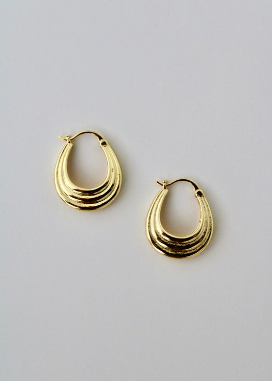 Gold hoop earrings on a light gray background
