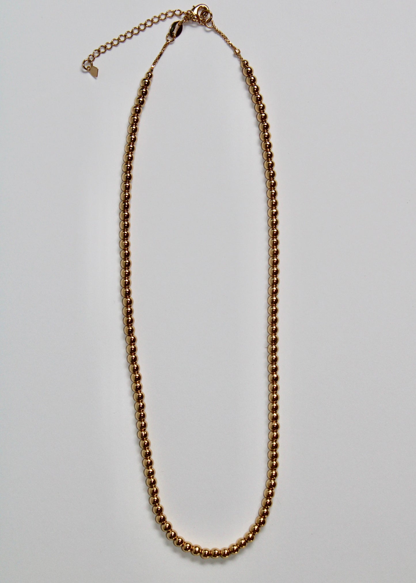 Gold chain necklace on a light gray background