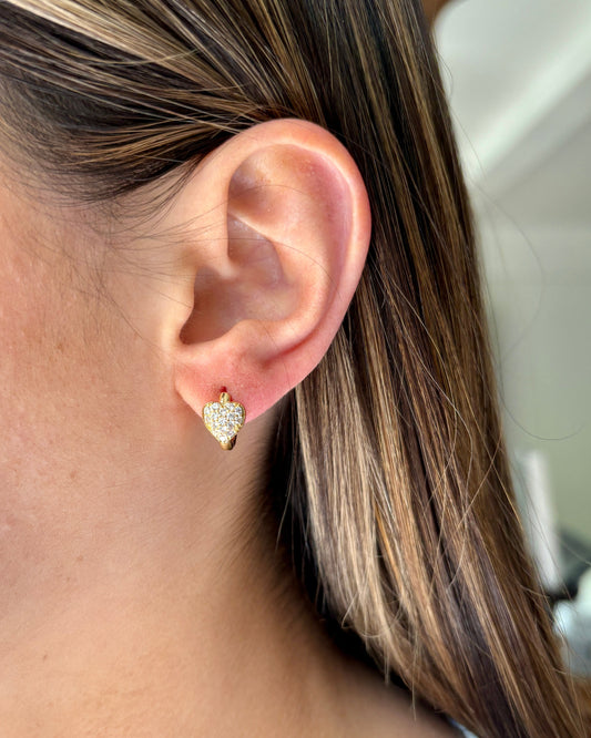 Close-up of an ear wearing a heart-shaped earring with a blurred background